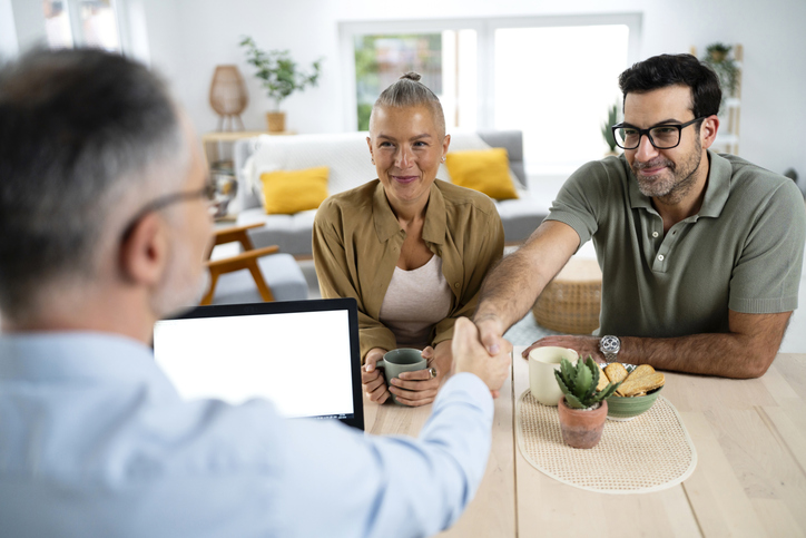 Insurance Advisor shaking hands with clients in a modern home