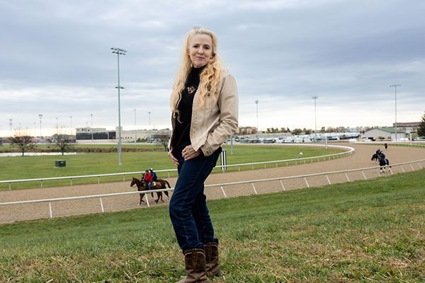 Monica standing in front racetrack with horses on track in the background