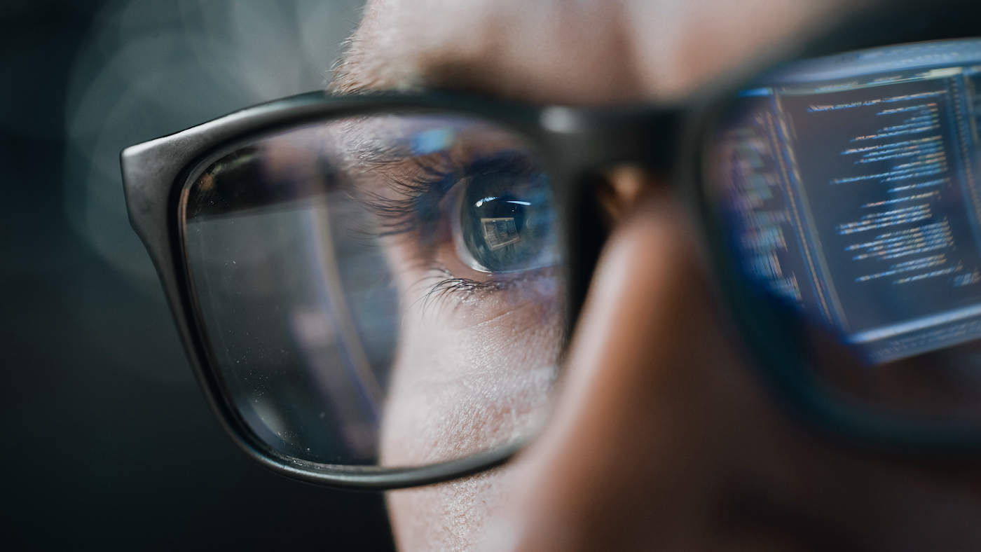 Lines of computer code reflected in eye glasses.