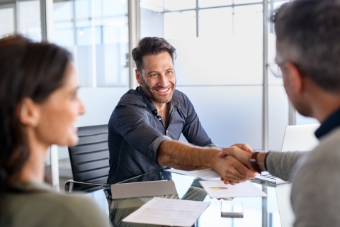 three insurance agents make a business deal around a table