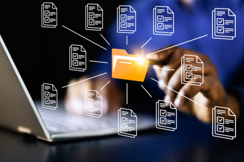 Young African-American businessman using virtual reality system to manage financial files on laptop for his cybersecurity company.