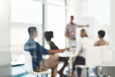 A blurred out image of independent insurance agents working in a glass conference room.