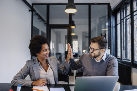 two business people high fiving over computers