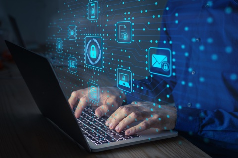 Hands typing on a laptop with graphics of locks, emails, laptops, PDFs laid on top.