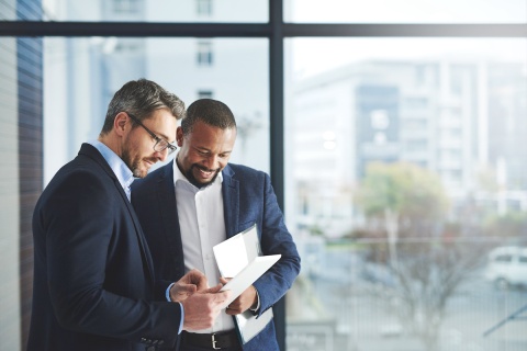 Two non captive insurance agents discussing documents and contracts in front of a big glass window.