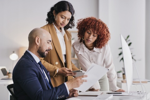 Three colleagues gathered around at a desk