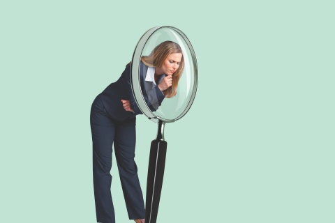 Women looking through a large magnifying glass.