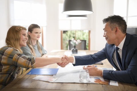 three people conducting business over a kitchen table