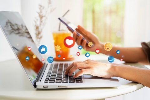 A young woman relaxing in a cozy cafe, holding a drink while using her laptop to represent the modern lifestyle and social media influence, with the focus on generating leads with real-time marketing campaigns and optimizing conversion rates in a digital setting.