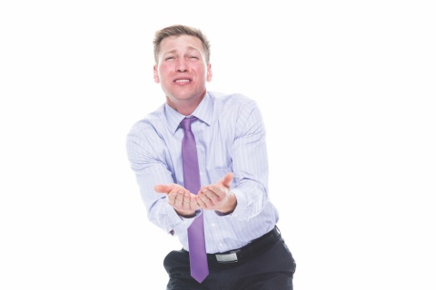 Man in a button down shirt and tie begging with his hands out.
