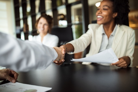 An independent insurance agent shakes hands with a client after selling specialty insurance coverage.