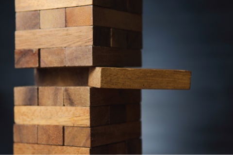 A stack of Jenga blocks with a piece pulled halfway out.