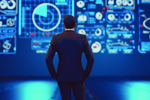 Man in suit looks at data screen