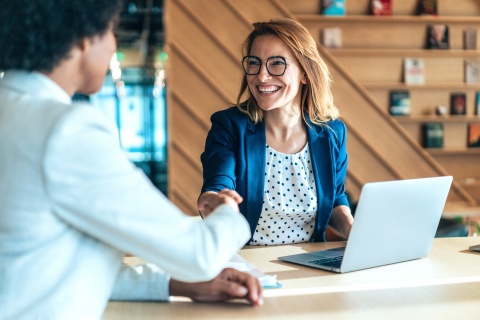 Corporate business team discussing strategies for Recruiting Insurance Producers in modern office. Two entrepreneurs shaking hands in board room meeting. Female manager leading discussion on new project with colleagues. Company owner meeting with employee in office.