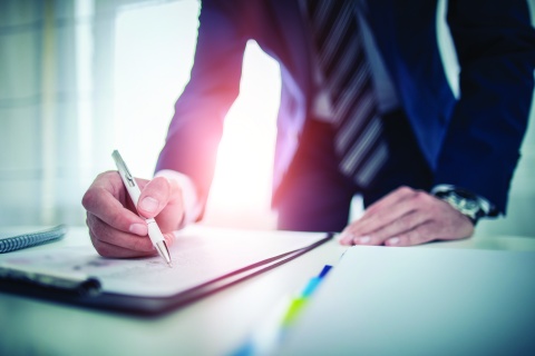 Man in a suit signing a piece of paper