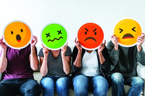 4 people holding emoticons with different unpleasant emotions over their faces