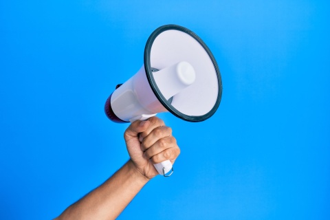 A hand holding up a megaphone against a blue background.