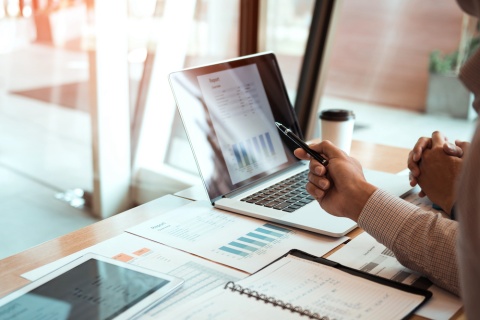 The owner of an independent insurance agent pointing to something interesting in a financial statement shown on a laptop.