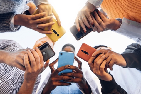 Teens in circle holding smart mobile phones.