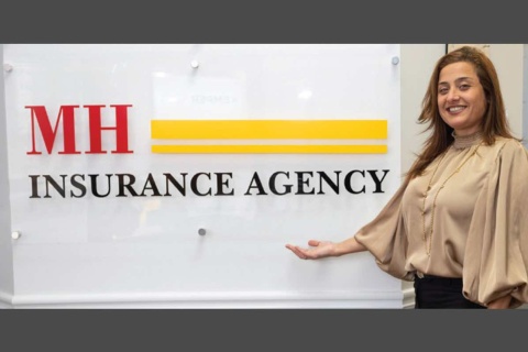 Martha Hernandez, owner of an independent insurance agency called MH Insurance Agency, stands in front of her office sign.