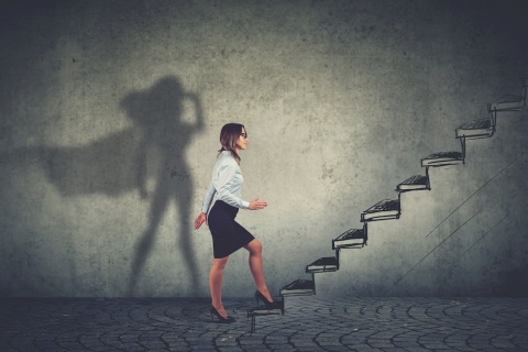 Young business woman climbing a set of stairs with her shadow in the background