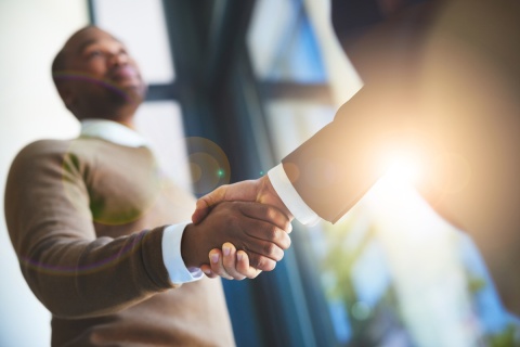 An independent insurance agent shaking hands with a customer after finalizing an insurance package.