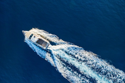 Fast speedboat racing along the open sea leaving white foam trail needs to be covered with specialty insurance.